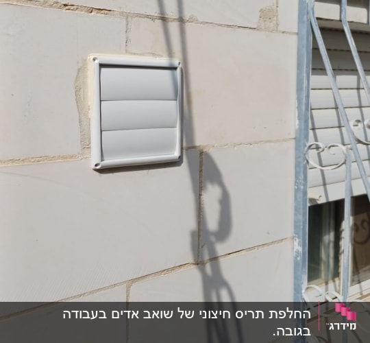 קיר עם פתח אוורור וצל של מתקן
